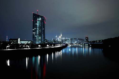 city lighted high rise building near body of water at nighttime town