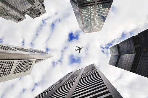 city low-angle photo of five buildings with airplane in the middle of picture skyscraper
