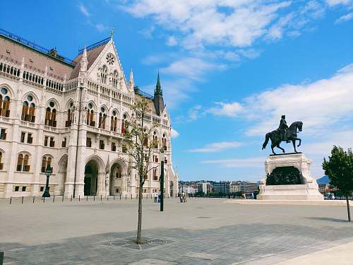 city man riding horse statuette in front of building downtown