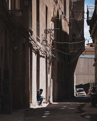 road man sitting near brown concrete building town