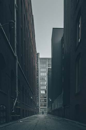city man walking in the middle of city buildings under gray clouds grey