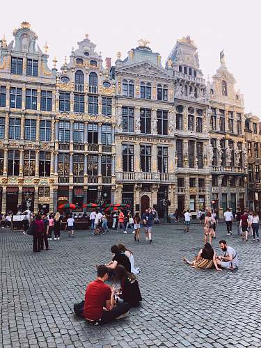 downtown people sitting and standing beside high buildings during daytime town