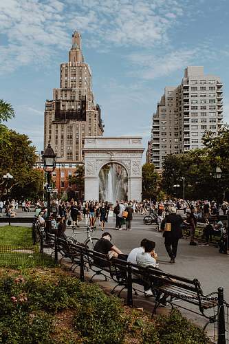 city people sitting and walking on park during daytime downtown