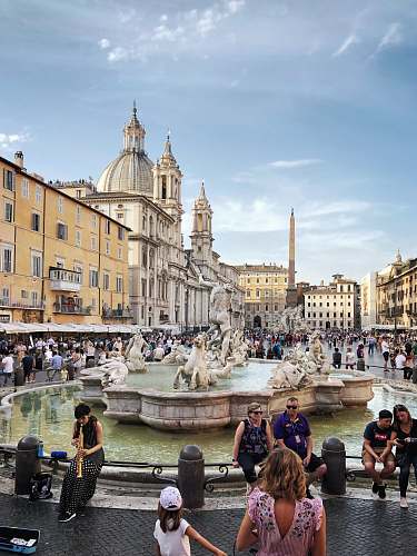 city people walking and sitting near water fountain during daytime downtown