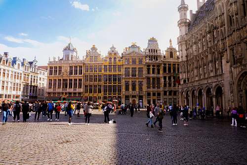 city people walking near Grand Palace, Brussels Town Hall under white and blue sky during daytime downtown