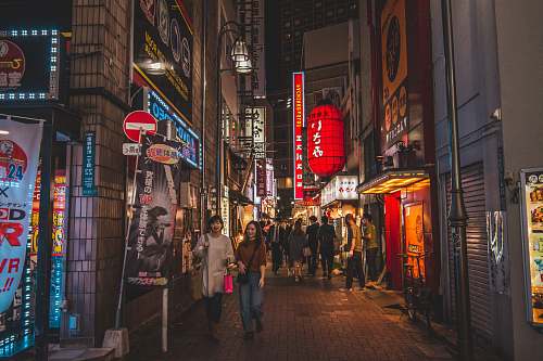 city people walking on pathway near buildings at night road