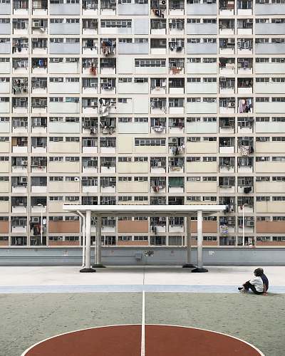 city two people sitting on concrete pavement in front of high-rise building high rise