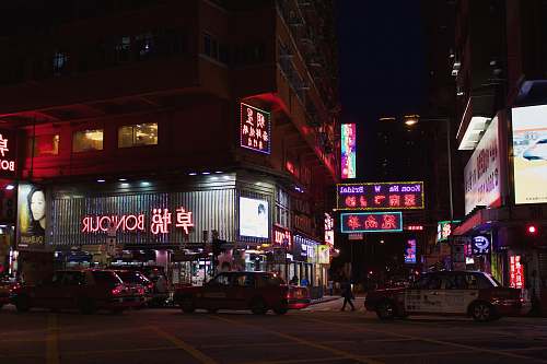 city vehicles on road with people walking near buildings during nighttime metropolis