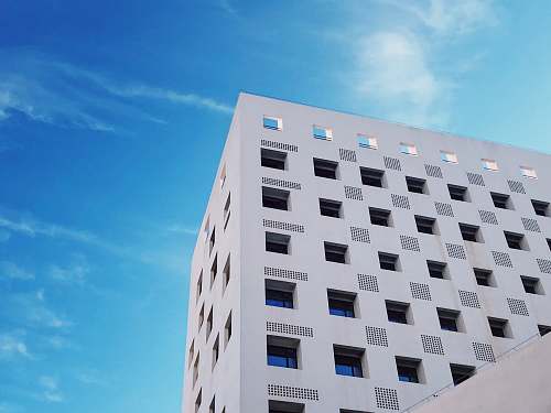 city white concrete high-rise building under blue and white skies high rise