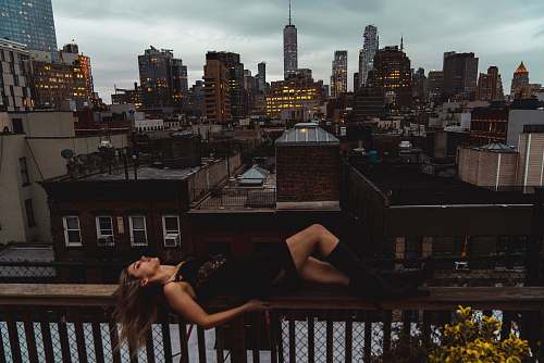 city woman lying down on a terrace overlooking city buildings metropolis