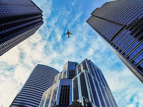 city worm's eye view of airplane passing by buildings skyscraper