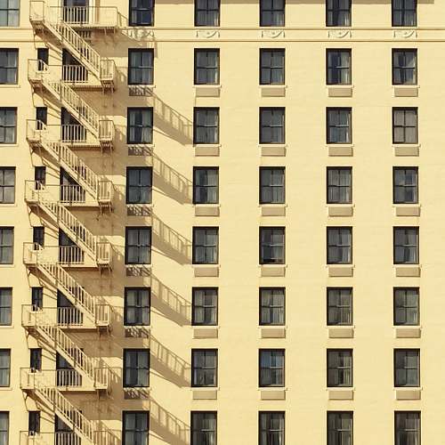 city yellow buildings with windows and emergency ladder high rise