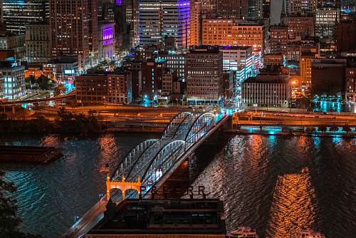 building aerial photography of bridge and buildings at night time town