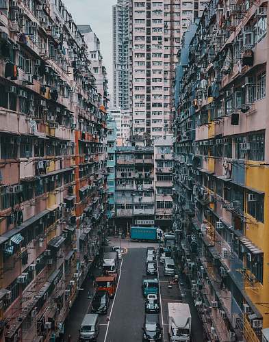 urban aerial photography of vehicles on road between concrete mid-rise buildings during daytime high rise