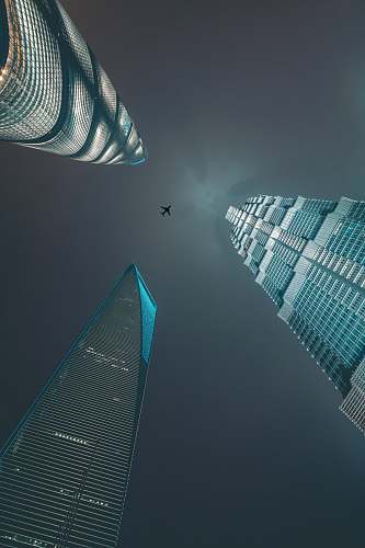 building airliner flying over three high-rise buildings town