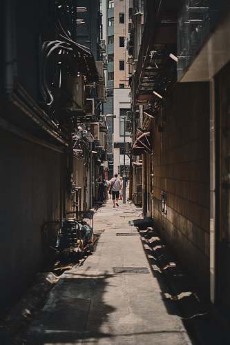 road alley photography of person walkway between building during daytime town