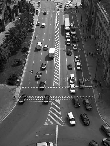 road birds eye view of vehicles on road between buildings black-and-white