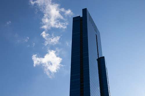 building blue glass walled high-rise building under blue and white skies high rise