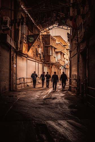 street five men walking on the pathway in between of buildings urban