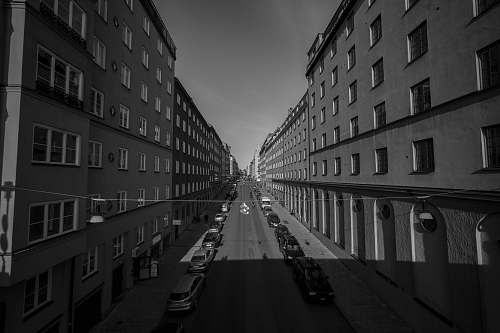 building grayscale photo of cars between buildings black-and-white
