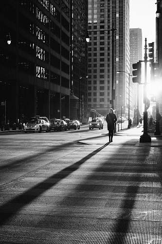 street grayscale photo of woman walking on road black-and-white