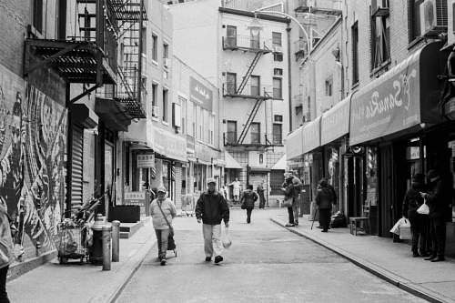 building grayscale photography unknown persons walking on alleyway black-and-white