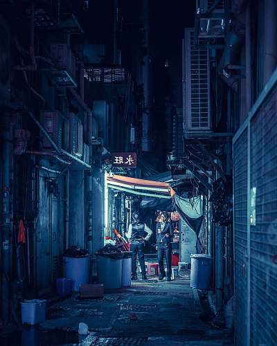 street landscape photography of two persons standing beside trash can alley