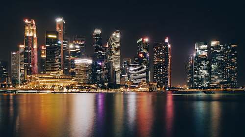building lighted city buildings near body of water during nighttime town