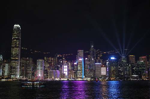 building lighted city buildings near calm sea during night time metropolis