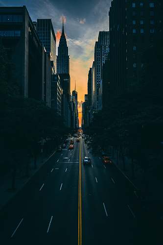 urban low light photography of vehicle crossing road between high-rise buildings manhattan