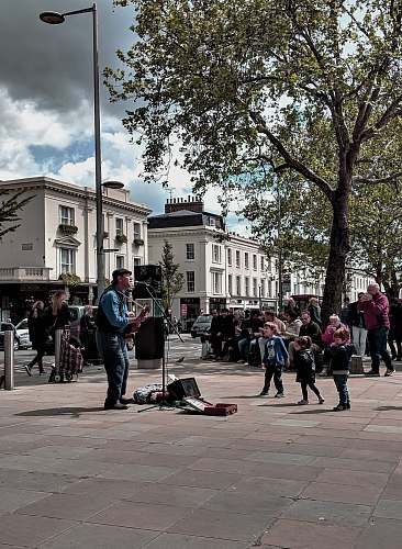 building man playing guitar surrounded with people downtown