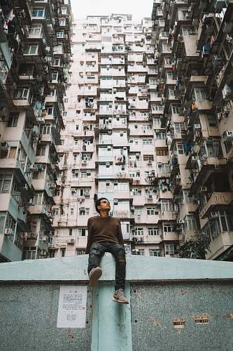 building man sitting near concrete building at daytime high rise