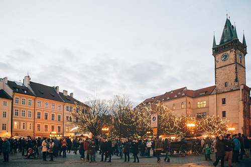 urban people standing near road beside brown castle under white sky during daytime downtown