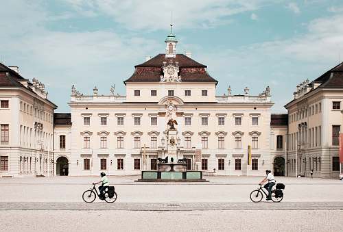 building person riding bike in front of white building during daytime town