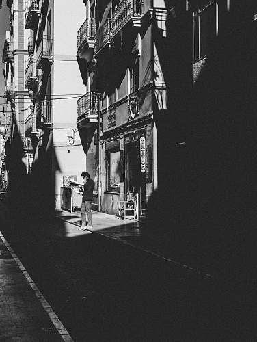 building person standing near building black-and-white