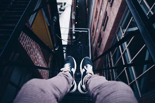 person person wearing pair of black Nike shoes sitting on metal frame feet