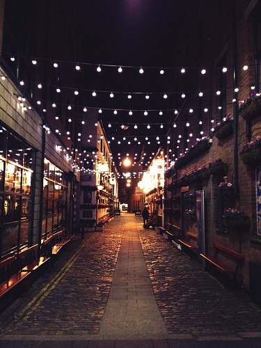 lights photo of narrow street with light bulbs during night time street