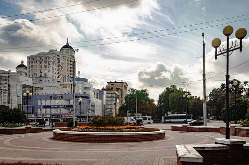 building round red brick landmark with flowers, lampposts, and benches near buildings downtown