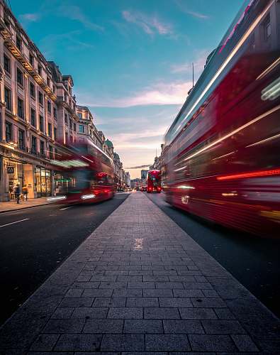 road timelapse photography of double decker bus on road between buildings london