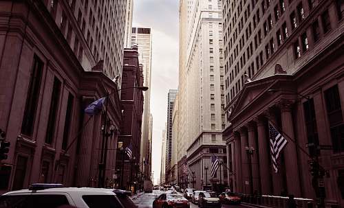building vehicles on concrete road between high buildings under white sky at daytime street