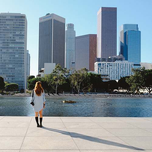 building woman stands beside river near city metropolis