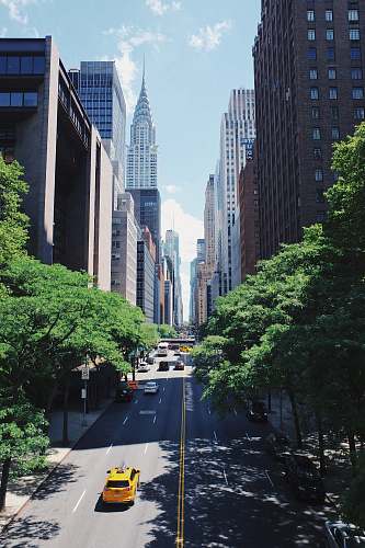 urban yellow car running on the street between the building during daytime new york