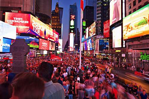 building crowd on road between buildings with electric billboards person