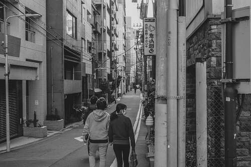 black-and-white grayscale photo of man and woman holding hands while walking street