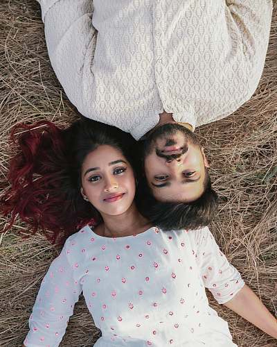 clothing high-angle photography of woman and man lying on brown grass sleeve