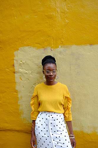 clothing woman in yellow crew neck long sleeve shirt leaning on yellow painted wall baltimore