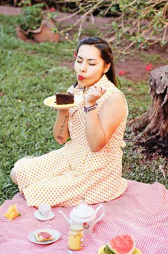 human woman eating cake while sitting on grass field person