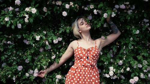 human woman in red and white polka dot dress standing beside white flowers person