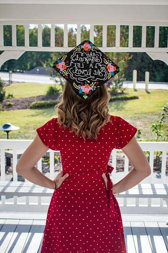 apparel woman wearing red dress and black academic hat facing backward clothing