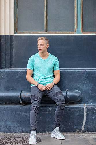 clothing man sitting on black pipe during daytime footwear
